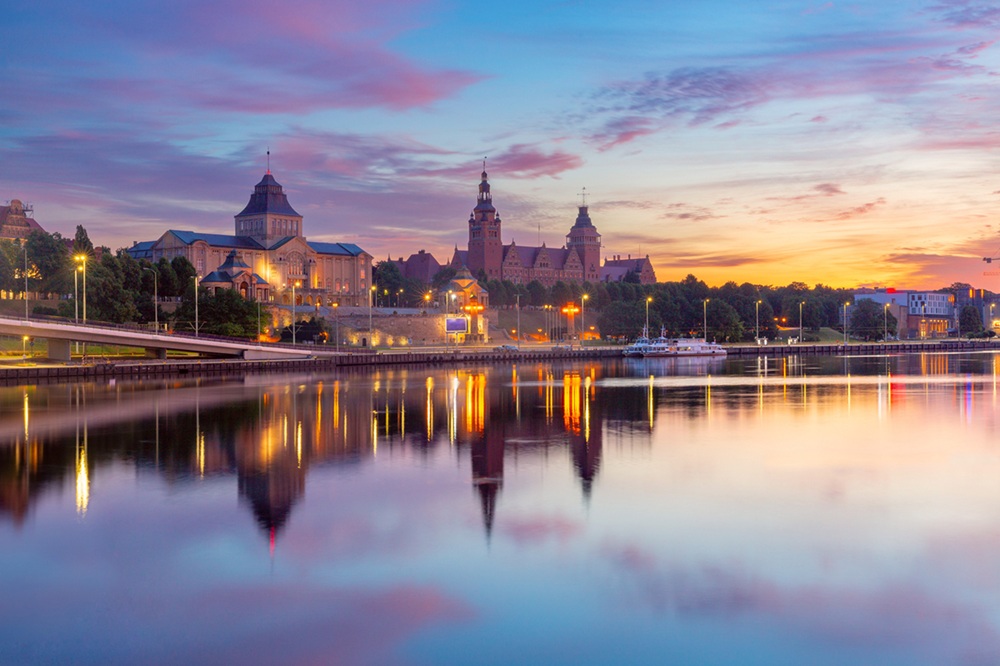 Sunset view of Szczecin riverfront Poland Sunset view of the Szczecin riverfront along the Oder River in Poland, featuring the illuminated Waly Chrobrego buildings and their reflection in the calm water